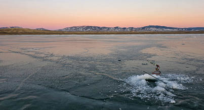 A person is on a surfboard in the middle of a lake, surrounded by mountains. AI generated content